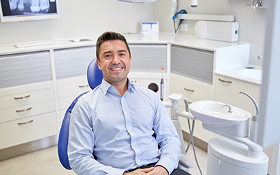 A male smiling sitting in a dental chair