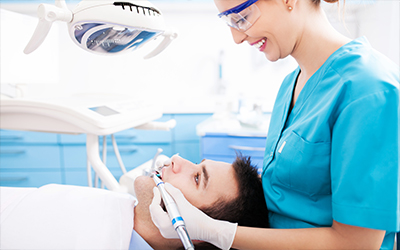 A female dental hygienist working on a male patient's teeth