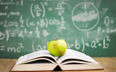 Book and apple with math concepts on a chalkboard behind it